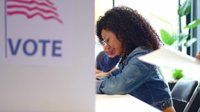 african american Person Voting in Election Booth. young woman focused on voting in an election booth during a United States election. elections, democracy, civic participation, and the voting process