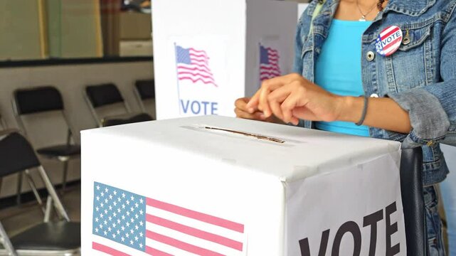 close up on the hands of a diverse group of people placing their vote ballot in the polling box, elections in united states