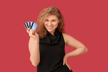 Beautiful young woman with credit cards on red background