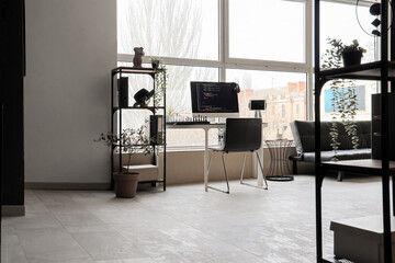 Interior of modern office with programmer's desk and shelf unit