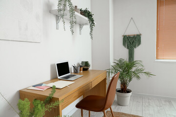 Interior of light office with workplace, shelf and green houseplants