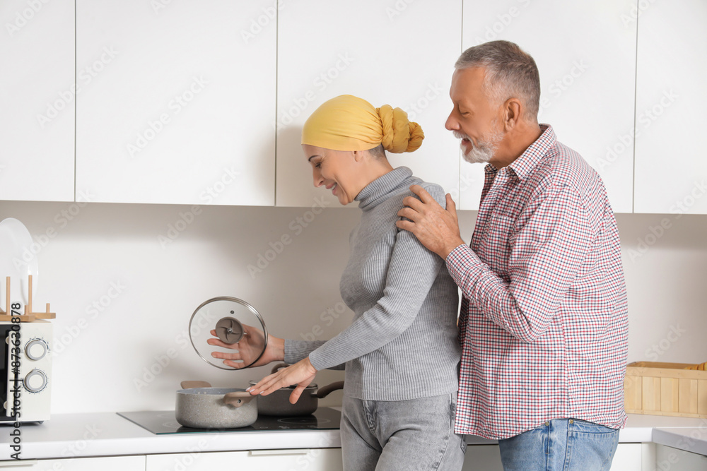 Poster mature woman after chemotherapy with her husband cooking in kitchen