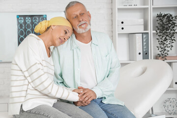Obraz premium Mature woman after chemotherapy with her husband sitting on couch in clinic