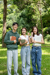 Group of cheerful Asian college students smile at the camera while standing in a park.