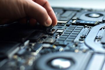 computer technician laptop motherboard repair technician The technician uses his hands to remove or...