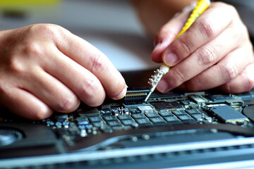 computer technician laptop motherboard repair technician The technician uses a screwdriver to separate the ribbon cable from The motherboard came repaired on the table.