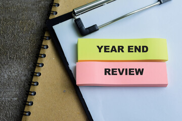 Concept of Year end Review write on sticky notes isolated on Wooden Table.