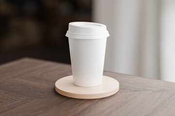White blank take away coffee cup on top of cylindrical wooden coaster for mockup presentation design rendering photoshop blank template with circular lid