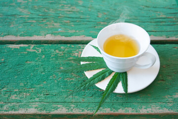 hot Cannabis or marijuanna drink in cup serve on hemp leaf on dish serve on old wood table with smoke