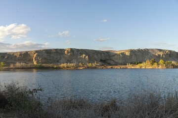 Scenic view of a lake with rocky cliffs and a clear sky during sunset.