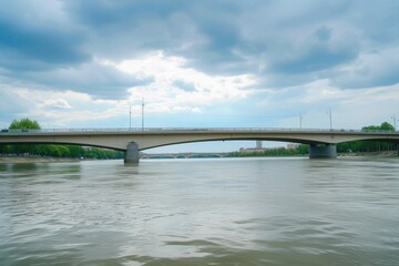 a bridge over a body of water under a cloudy sky, modern bridge spanning a wide river