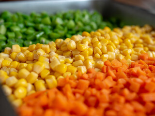 Assorted vegetables (carrots, corn and green beans) arranged in rows