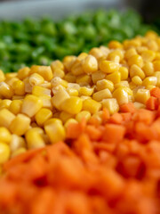 Assorted vegetables (carrots, corn and green beans) arranged in rows