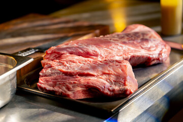 close-up in a restaurant on an iron table there are professional dishes with fresh piece of meat retraining for marinade