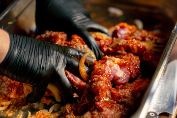 close up in a restaurant in a rib bar in the central hall chef in black gloves kneads meat in a...
