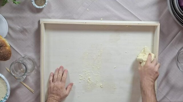 Top down overview of chef kneading handmade busiate pasta dough ball on prep surface