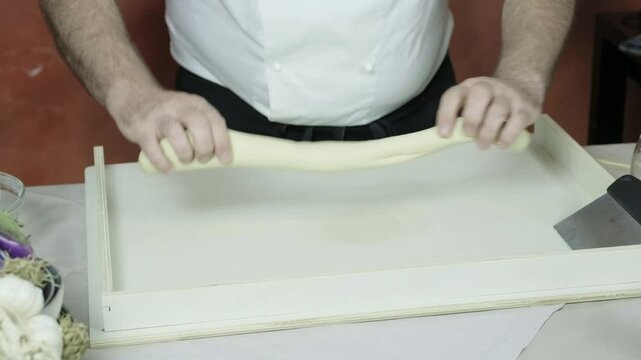 Chef skillfully rolls and spreads dough out then divides it using dough cutter
