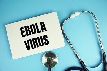 Ebola Virus text on paper card with stethoscope top view on blue background