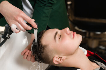 Barber shampooing washing a male clients head in the sink.