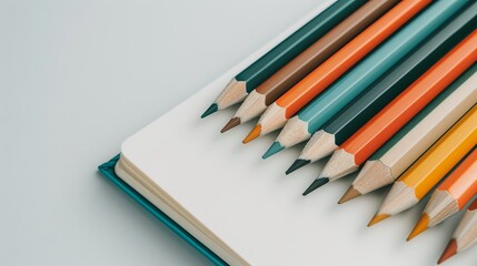 Obraz premium Close-up of colored pencils, their tips freshly sharpened, placed next to an open sketchbook, showcasing drawing and writing tools in detail