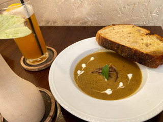 Mushroom Soup in craft bowl on wooden table. Mushroom champignon soup with bread and fresh mushrooms. ZUPPA DI FUNGHI (Mushroom soup served with sourdough). top view.
