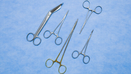 Fototapeta premium Flat lay of stainless forceps medical scissors placed on a blue background. Medical instruments . Medical Surgical Instrument. Equipment used in surgery.