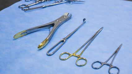 Fototapeta premium Stainless forceps medical scissors placed on a blue background. Medical instruments . Medical Surgical Instrument. Equipment used in surgery.