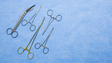 Flat lay of stainless forceps medical scissors placed on a blue background. Medical instruments . Medical Surgical Instrument. Equipment used in surgery.