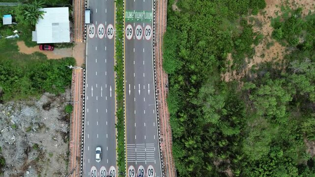 Aerial view of a busy urban intersection with multiple lanes of traffic, marked pedestrian crossings, and landscaped medians.