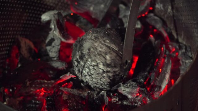 Roasted breadfruit in open fire, man turning the breadfruit to check roasting, traditional Seychelles food, Mahe, Seychelles 4k 24fps 005