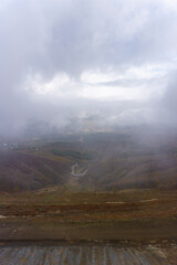 Fototapeta premium Top view of the turn of the road in the canyon, villages in the clouds and fog. Mountains hidden in clouds and fog