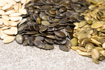 Unpeeled and peeled pumpkin seeds close-up, top view.