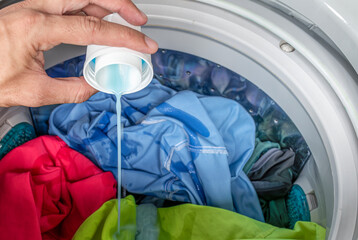 Pour laundry detergent with colorful clothes in washing machine