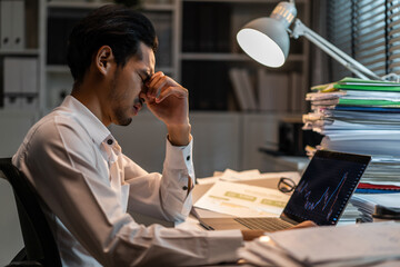 Frustrated Asian young businessman worker working on table in office.