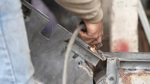 a worker is welding an iron plate in a workshop