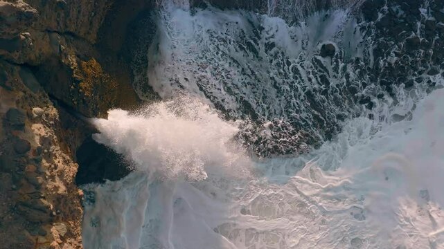 Waves squirting through chutes in rough seas in Piha, Auckland, New Zealand.