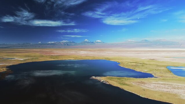 Aerial Scenic Shot Of Glacier On Mountains, Drone Descending Forward Over Salt Lake During Sunny Day - Atacama Desert, Chile
