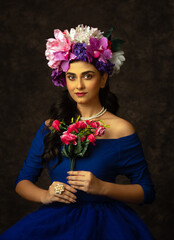 Portrait of a beautiful fashion model dressed in blue holding a bunch of flowers. Useful for advertising purpose.