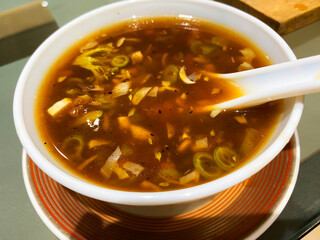 Hot and sour soup, served in a classic ceramic bowl, is a tantalizing blend of spicy and tangy flavors that warms the soul. 