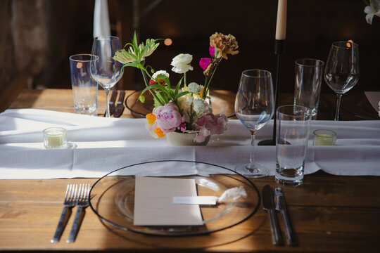 A wedding table setting with a clear glass plate, delicate floral centerpiece, and modern decor.