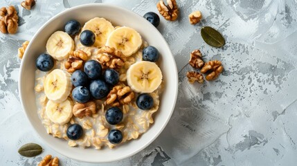Fototapeta premium A bowl filled with oatmeal topped with fresh blueberries and crunchy walnuts. The concept of a healthy breakfast.