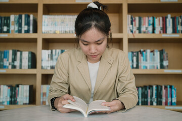 In the library, a woman, deeply engrossed in reading, stands by the bookshelf, surrounded by books,...