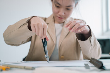 In her office, the professional woman architect meticulously uses a compass in hand to refine the...