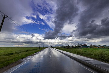 A road with a lot of rain and a few birds flying in the sky