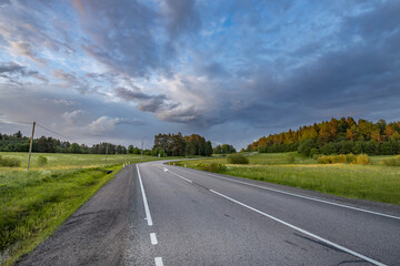 A road with a few trees in the background and a cloudy sky