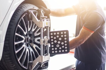 Vehicle wheel alignment. Tyre wheel alignment. Technician placing sensors to tires for Alignment....