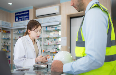 Obraz premium The pharmacist provides medicine to the engineers who come to buy medicine in the pharmacy.
