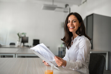 Portrait of young businesswoman smilling and holding paper documents in her hands