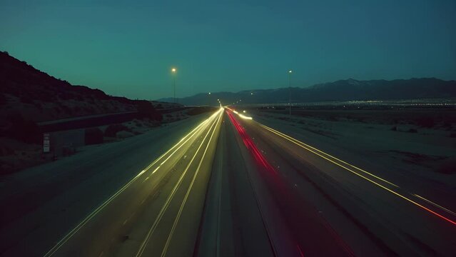 Rows of bright car light trails stretch out in the distance painting a surreal scene on the deserted highway.