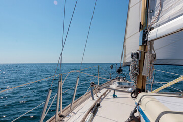 Fototapeta premium Luxury cruise on a sailing rigged yacht under a genoa and mainsail sailing in a light wind during the regatta. Yachting as a luxury sport and great vacation. View from the deck 